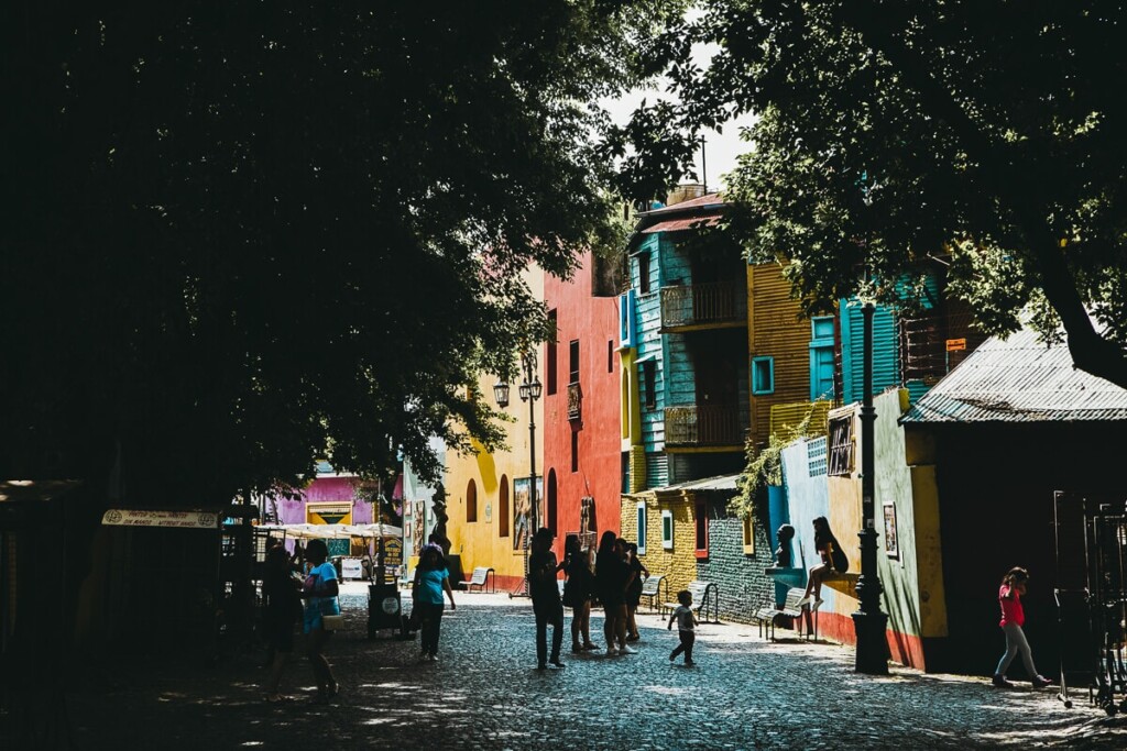 A wall of patchwork colors and a cobblestone path covered by trees