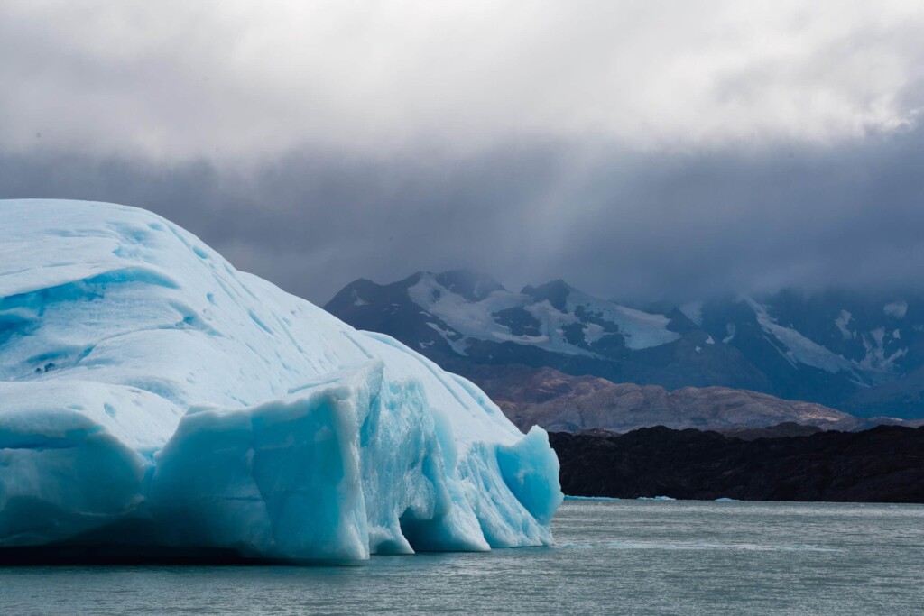 A huge bright blue iceberg floats in the water of a lake in Argentina