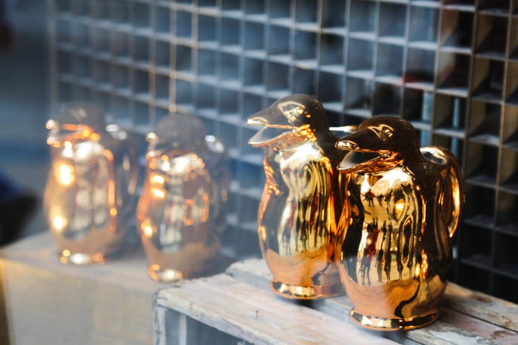 Four golden pitchers in the shape of penguins in a storefront window
