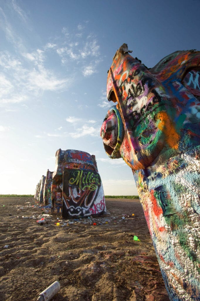 Cadillacs stick out of the desert at a 90 degree angle covered in graffiti