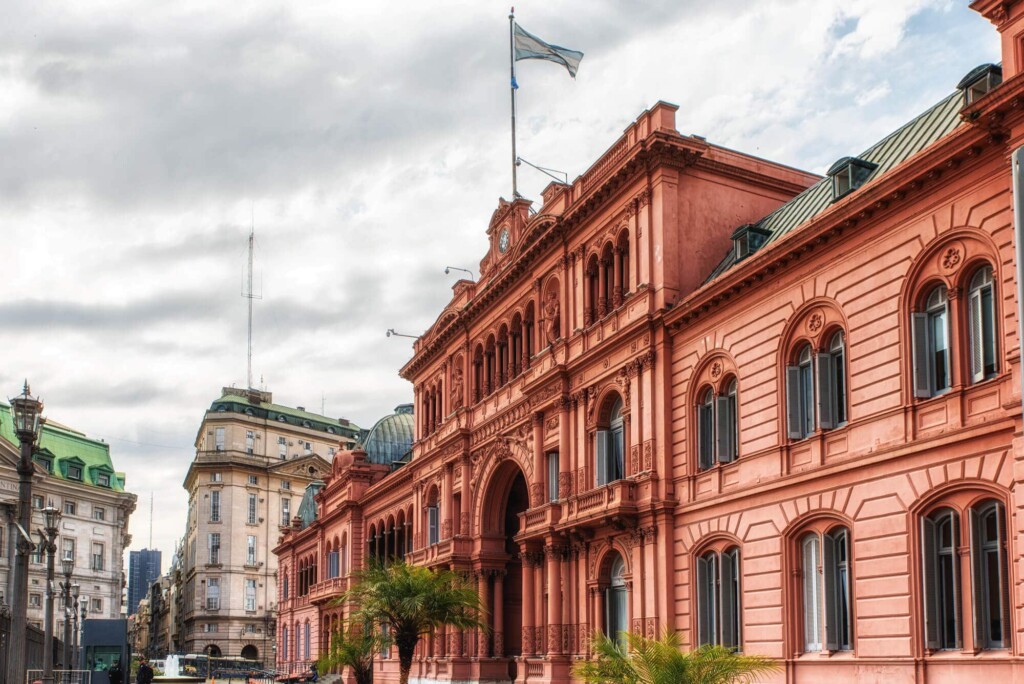 A pink government building with a blue and white flag flying overhead