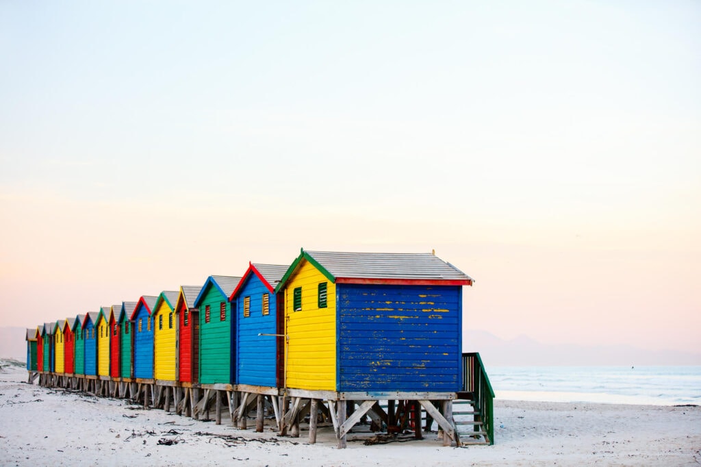 A row of wooden huts painted in rainbow colors on the beach