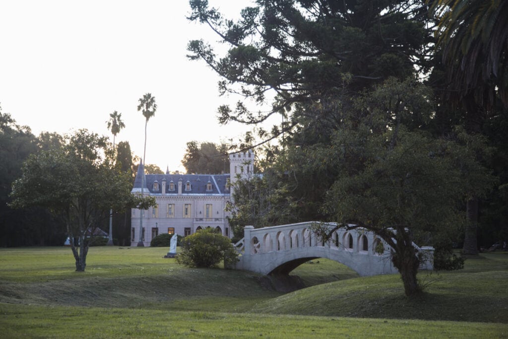 A French castle in the background with a stone bridge over a ditch