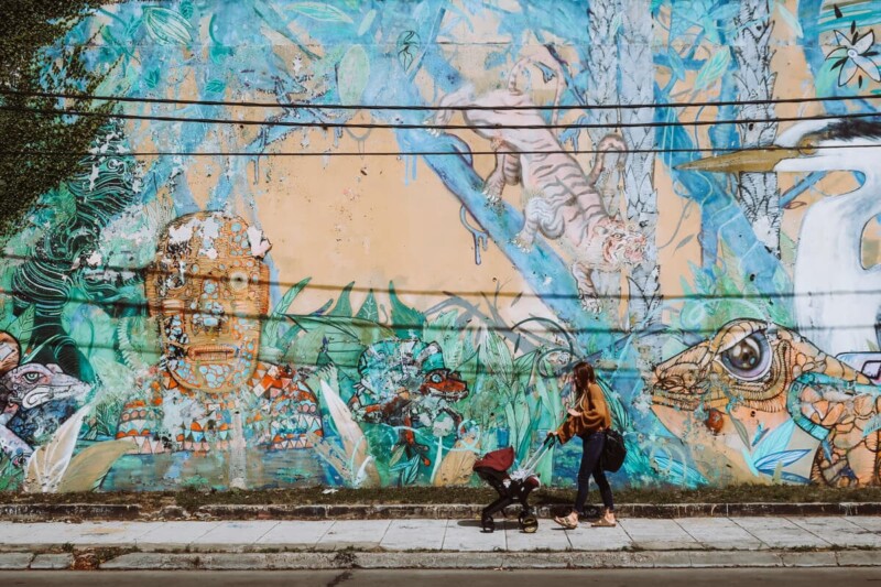 A woman pushes a stroller in front of a mural