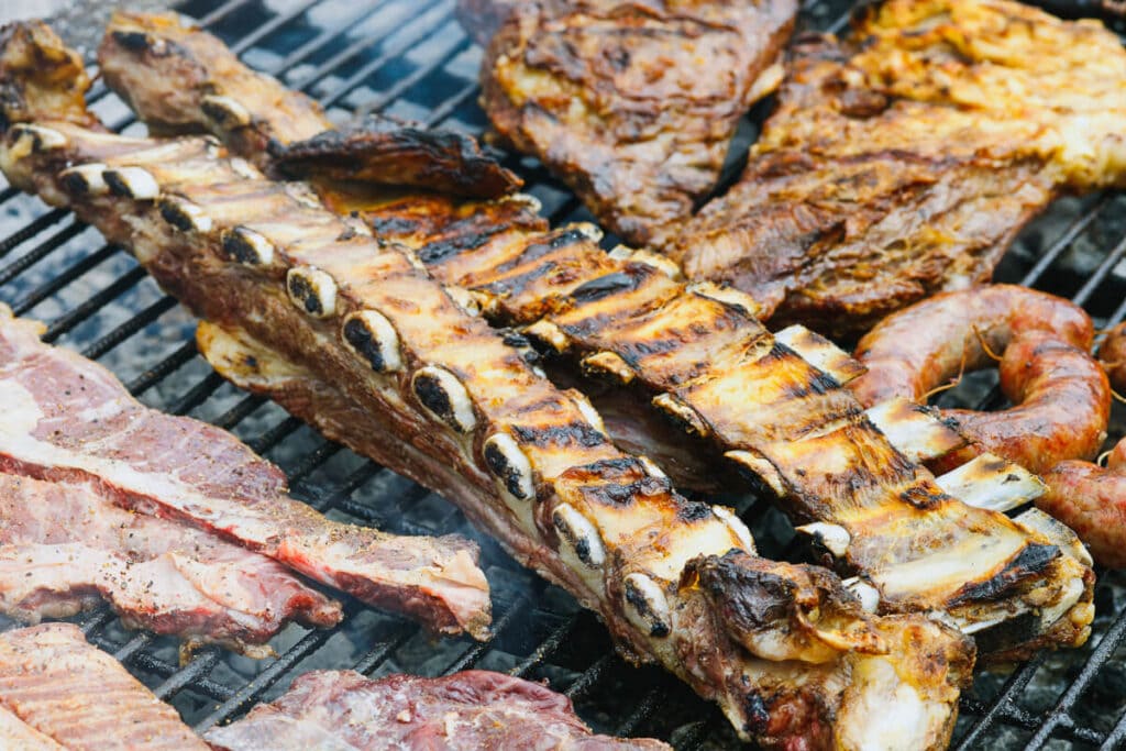 A rack of ribs on a grill with other cuts of meat