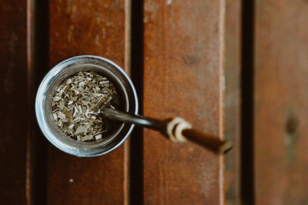 A cup of Yerba Mate and a bombilla straw on a wooden deck