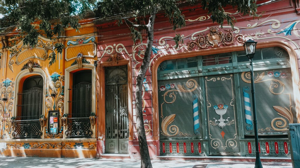 Two colonial style buildings covered in the floral swirly Fileteado style of painting typical to Buenos Aires