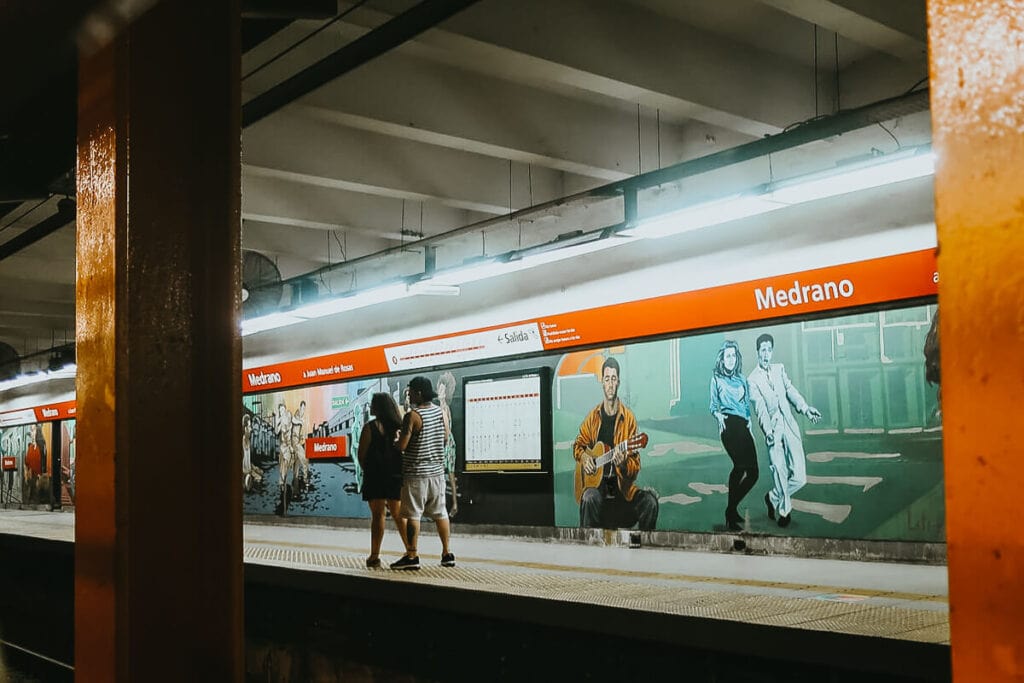 A man and a woman walk down a subway platform