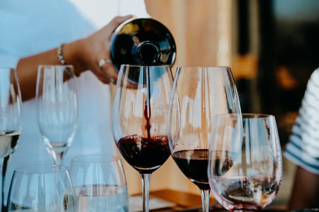 A woman pours red wine into a glass