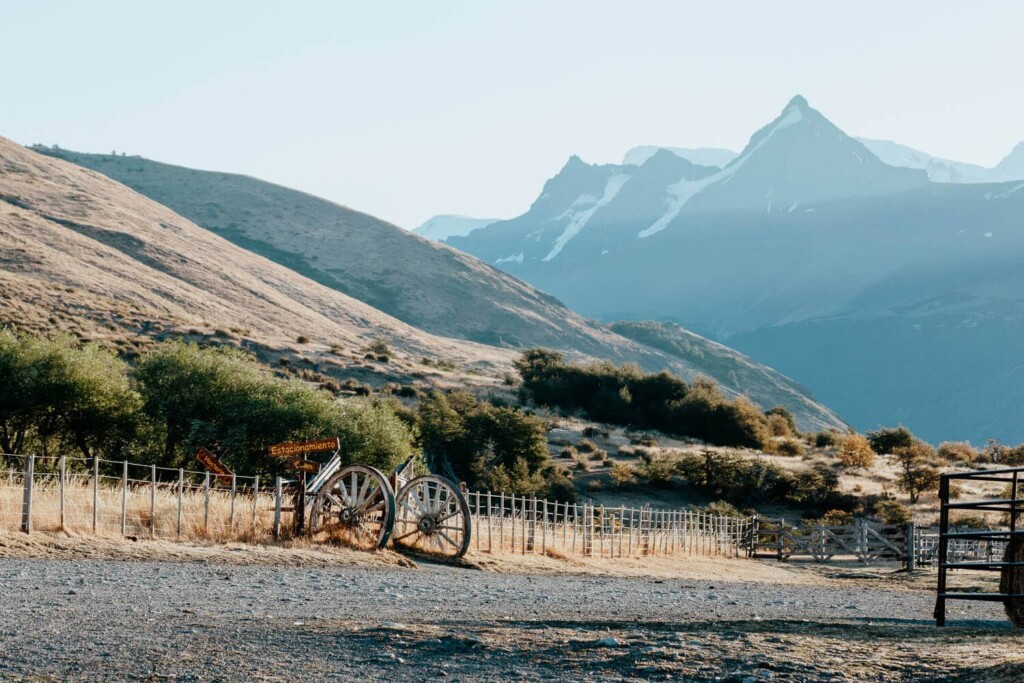 Mountains in the background are bathed in the sunset behind a fence at an El Calafate ranch.