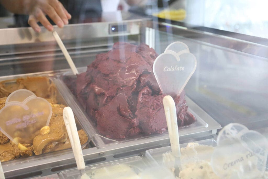 A tub of dark purple Calafate ice cream with a spatula in it ready to be served