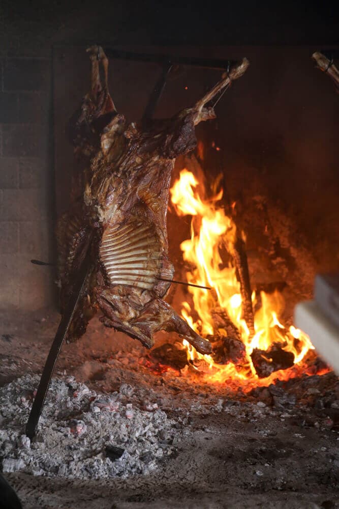 Lamb grilling over a fire hung from a metal cross in Patagonia