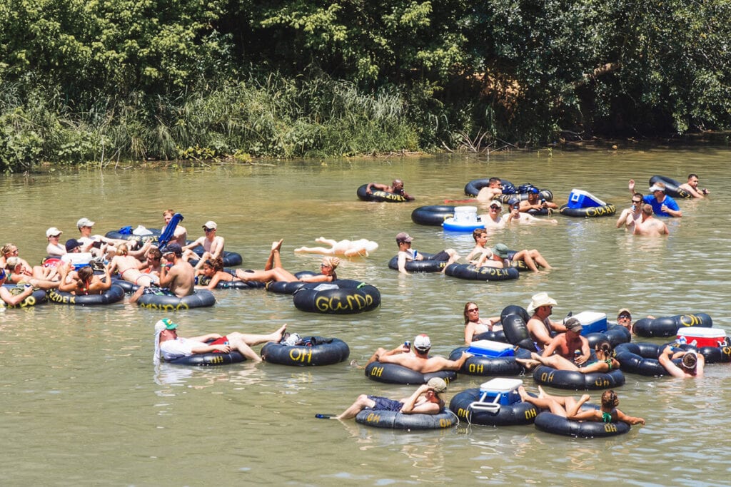 A bunch of people floating on innertubes float down a river