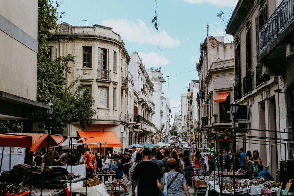 A sea of people walk down a street at an outdoor flee market