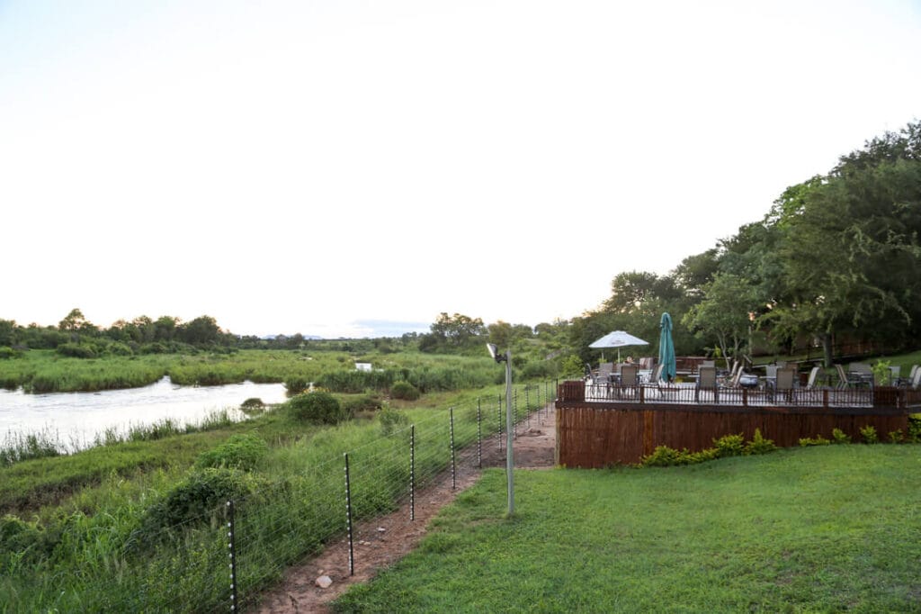 A wooden deck with lounge chairs on a grassy hill by a river