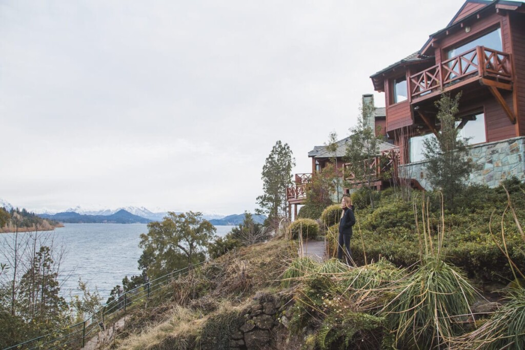 A woman on a sidewalk in front of wood cabins on a lake