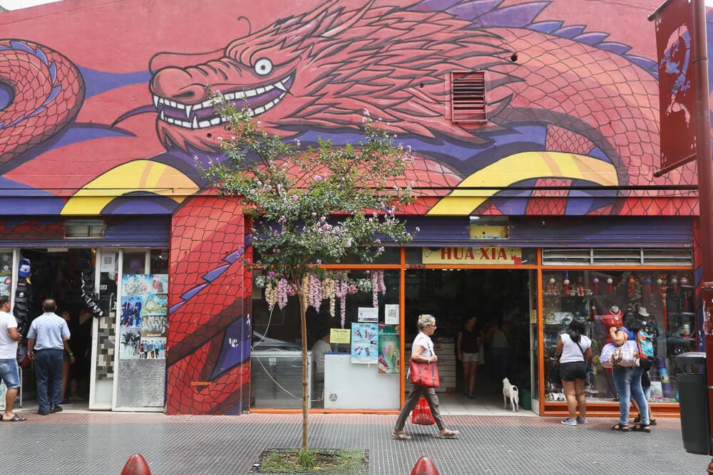 A woman walks in front of a storefront with a dragon painted on the facade