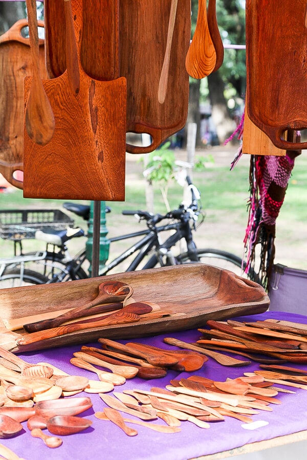 Wooden serving platters and spatulas on a purple cloth in a market