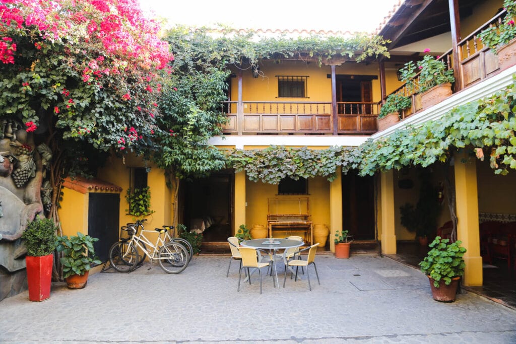 Bicycles and a table sit in the courtyard of a two story colonial style home