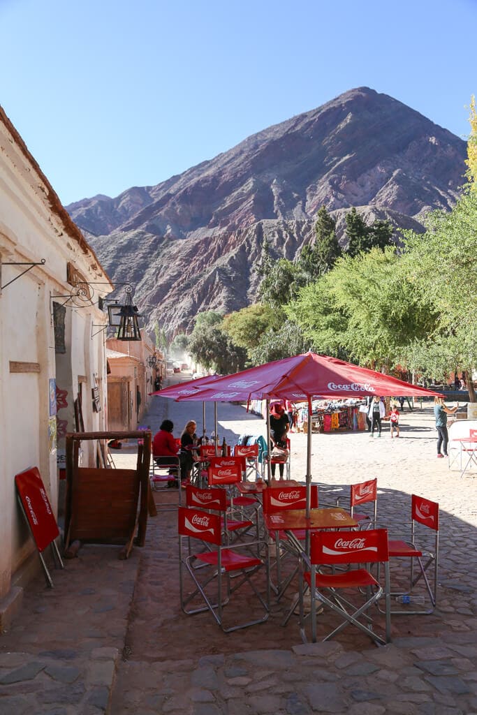 Red tables and chairs on the sidewalk of a restaurant