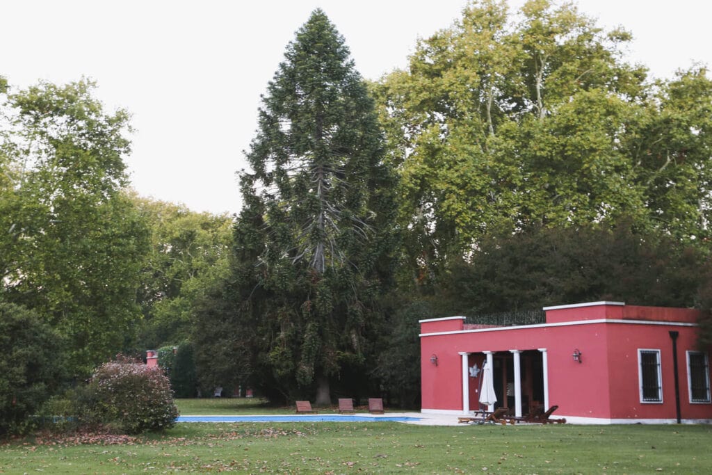 A red building by a pool surrounded by trees