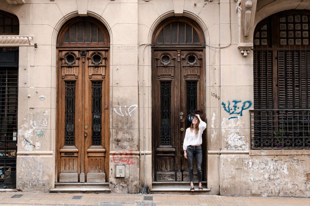 A woman stands in front of tall wooden door