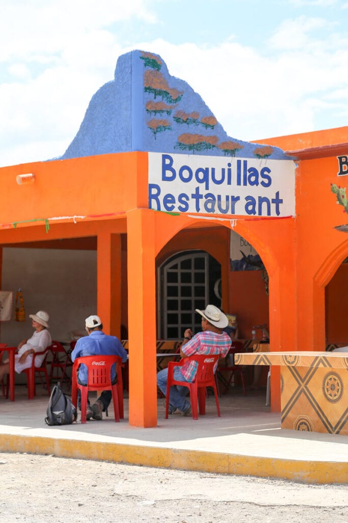 People sit in plastic chairs drinking at Boquillas Restaurant