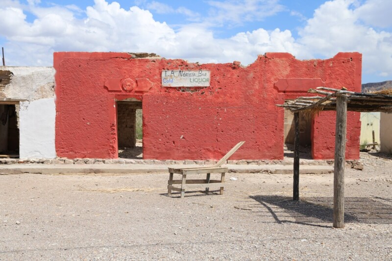 The remains of a ruined red adobe building in the desert