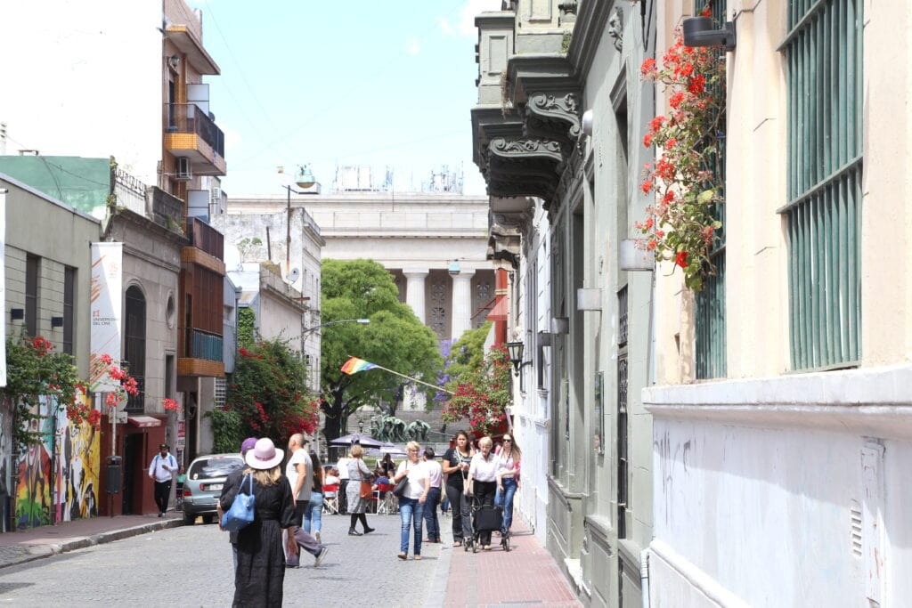 People walking down a street towards a columned building