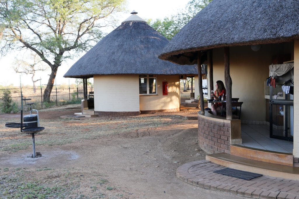 A woman sits at a table on the porch of a round hut