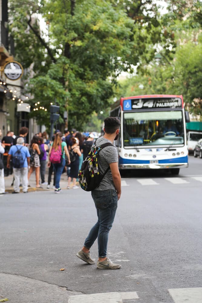 A man waits to cross the street as a city bus drives by