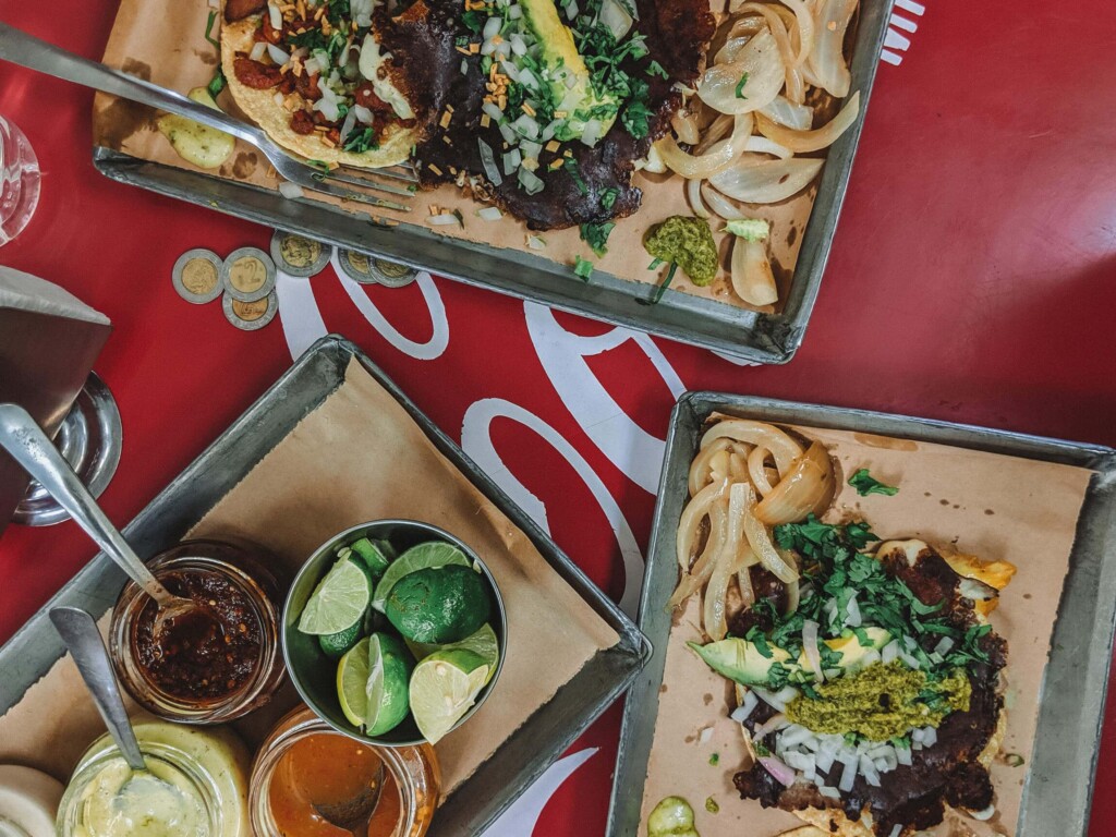 Three platters of tacos on a red table