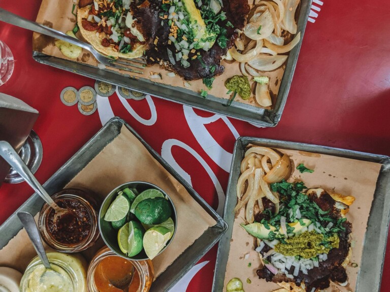 Three platters of tacos on a red table