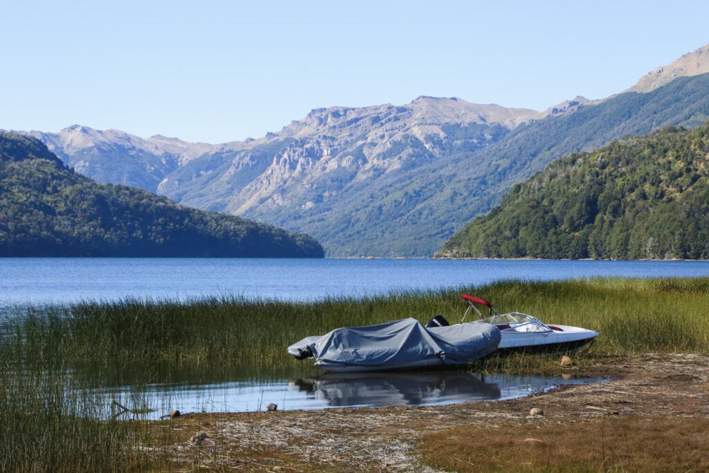 Two small boats sit in the shallow waters among grass at a lake