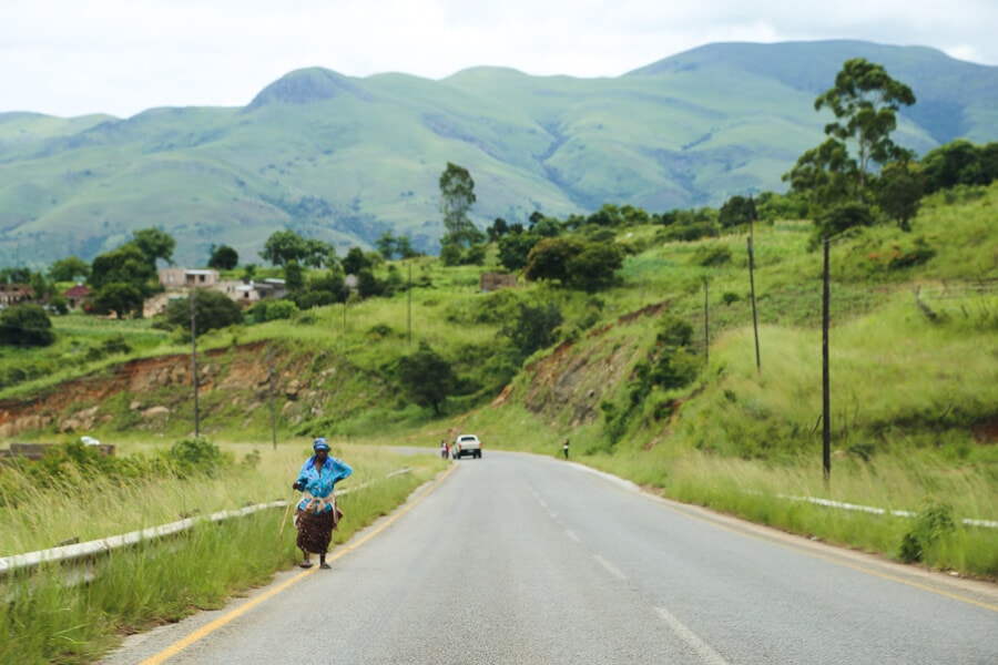 A woman walks next to a highway