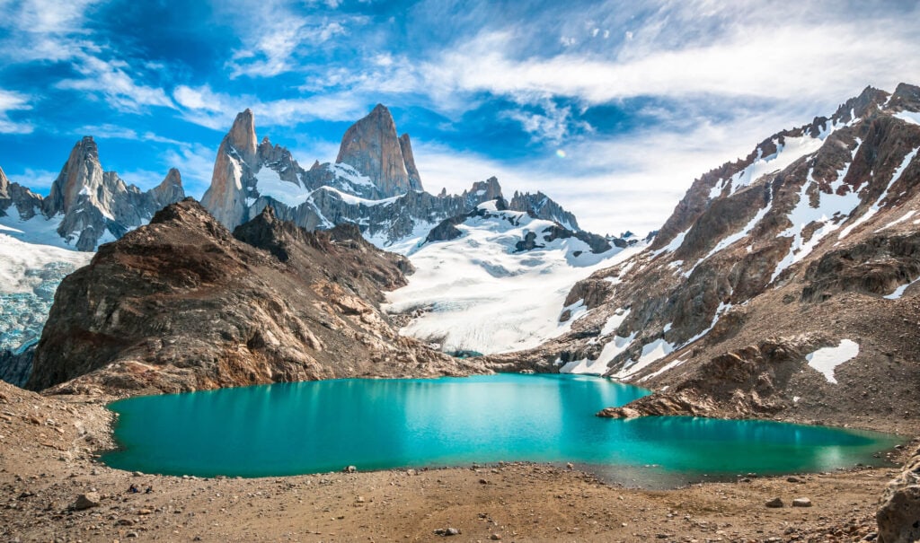 A turquoise lake in front of snow covered mountains