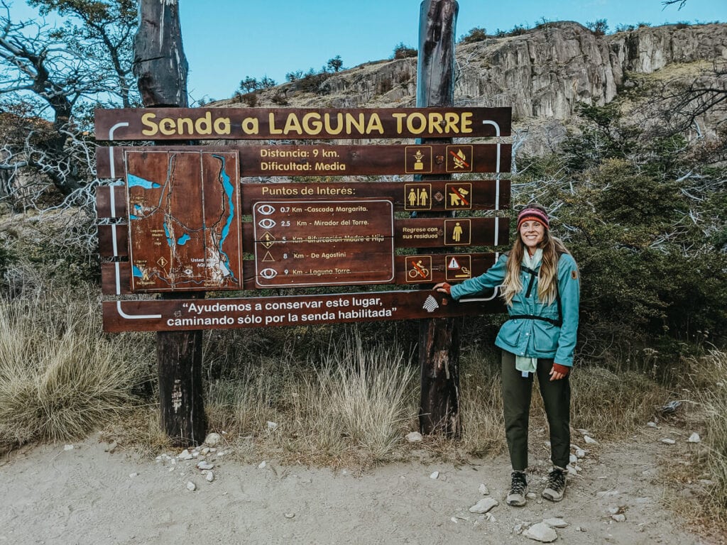 A woman poses in front of a sign