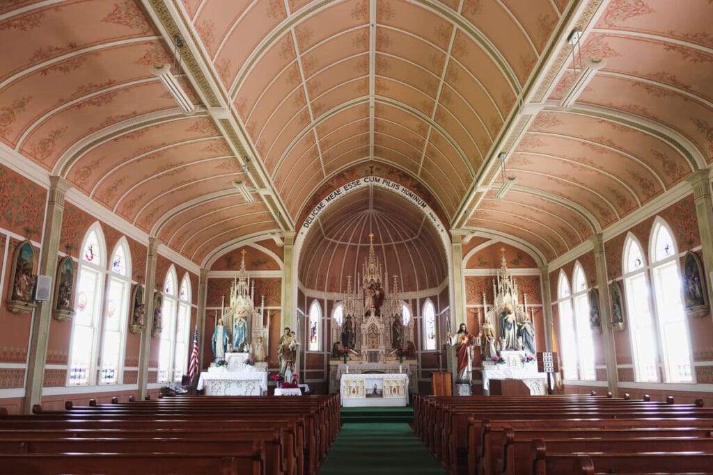 Wooden pews inside a pale pink church 