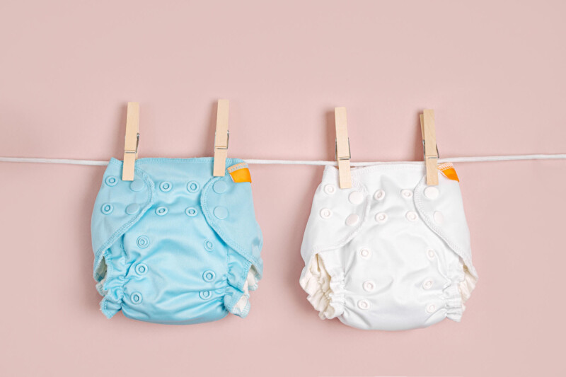 Two cloth diapers hang on a clothes line by clothes pins