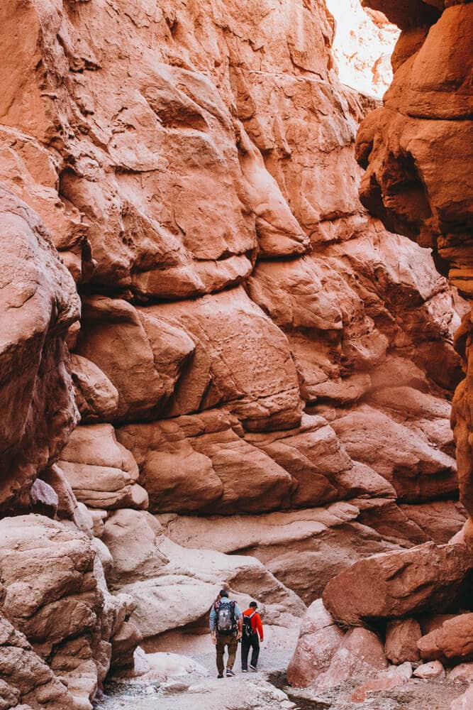 Two men walk through a red canyon