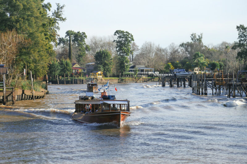 A wooden boat advances down a river