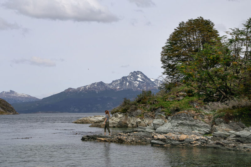 A woman stands on a rocky outcrop of a lake