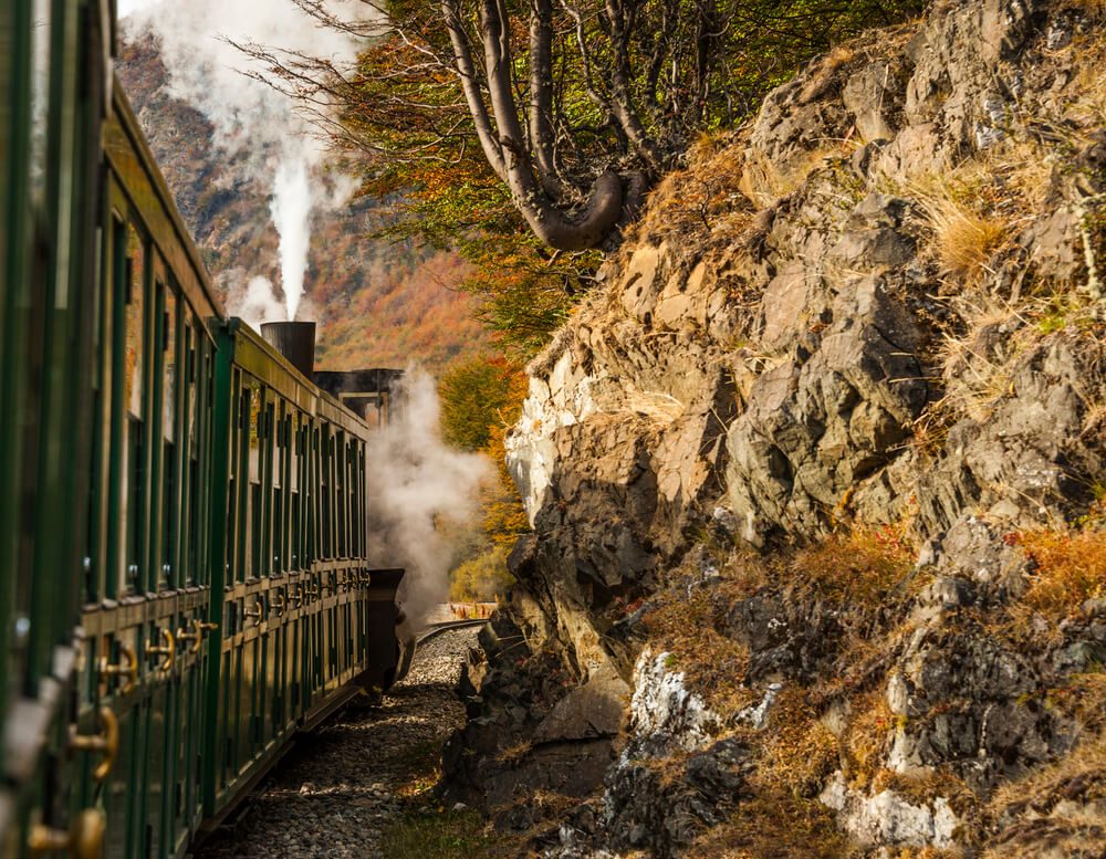 An old steamer train goes around a bend in the mountains