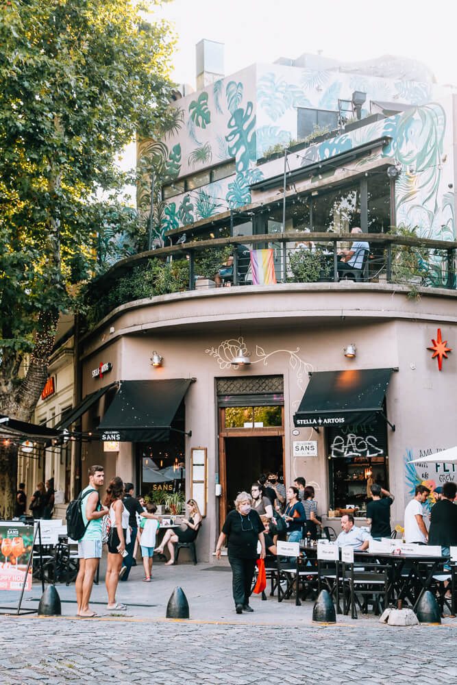 People crowd outside a restaurant on a street corner