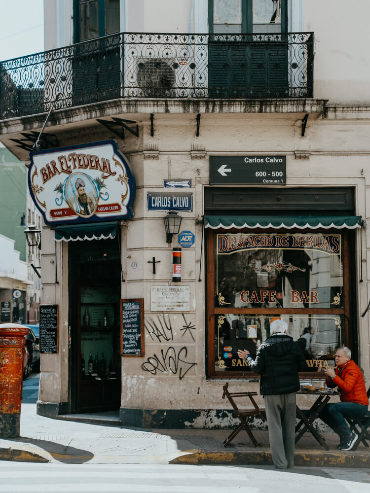 Two men eat at a table outside a bar in San Telmo