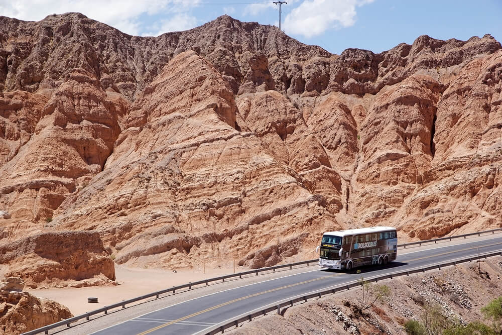 A two story bus drrives down a highway in Argentina's Northwest