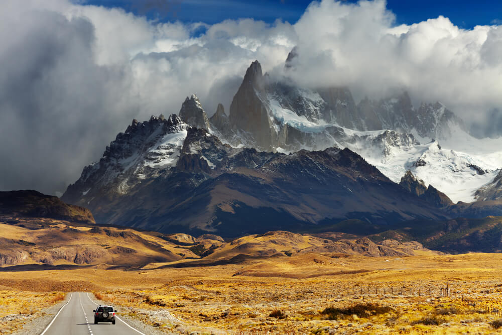 A car drives down a highway towards the mountains in Argentina