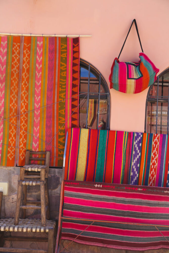 Woven tapestries hang on the wall outside a store in Purmamarca Argentina