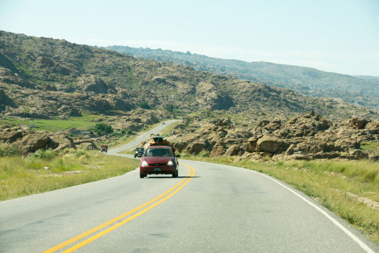 A red car drives down the highway in the Cordoba Sierras on a Argentina road trip