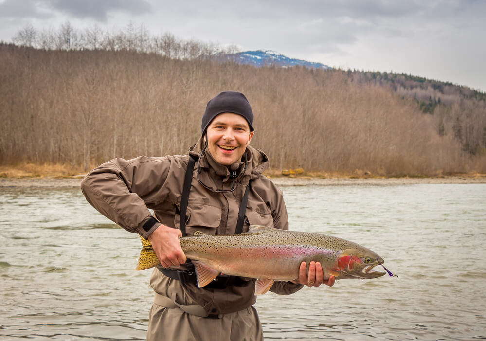 A man holds a large rainbow trout fishing in Bariloche